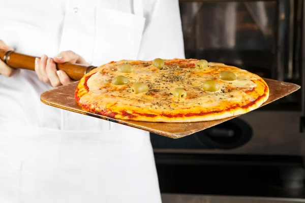 Koch hält Pizza auf Schaufel — Stockfoto