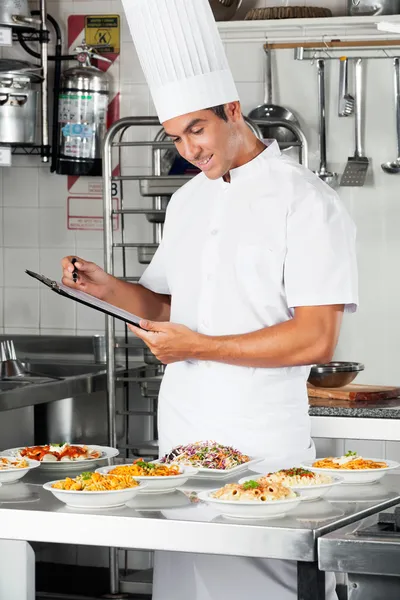 Chef joven con portapapeles en la cocina — Foto de Stock