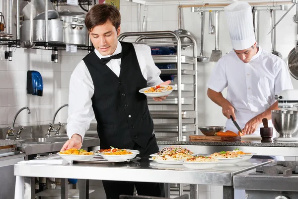 Cameriere e chef che lavorano in cucina commerciale — Foto Stock
