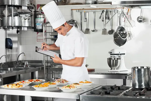 Chef con portapapeles pasando por la lista de verificación de cocina —  Fotos de Stock