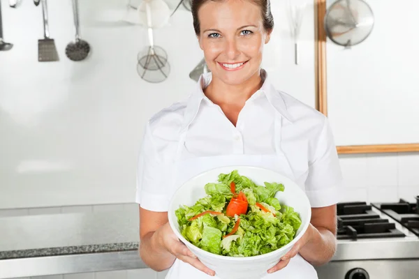 Chef feminino apresentando tigela de salada — Fotografia de Stock