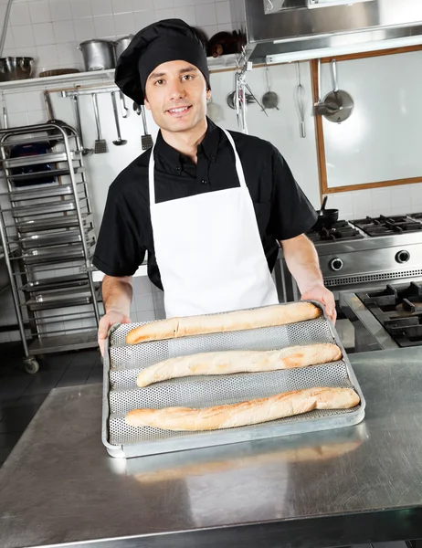 Mužský šéfkuchař ukazující upečený chléb šišky — Stock fotografie