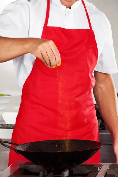 Szef kuchni dodając kurkuma w proszku na patelni — Zdjęcie stockowe