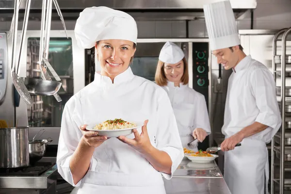 Glücklicher Koch präsentiert Gericht in der Industrieküche — Stockfoto