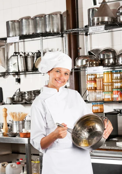 Vrouwelijke chef-kok mengen ei met draad vliegenmepper in kom — Stockfoto