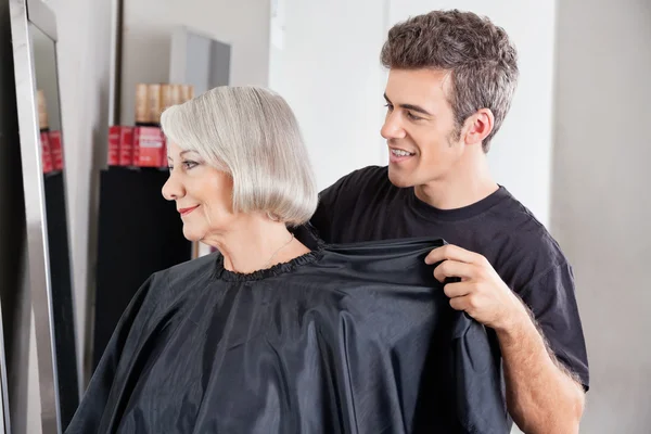 Ta bort klientens förklädet efter frisyr frisör — Stockfoto