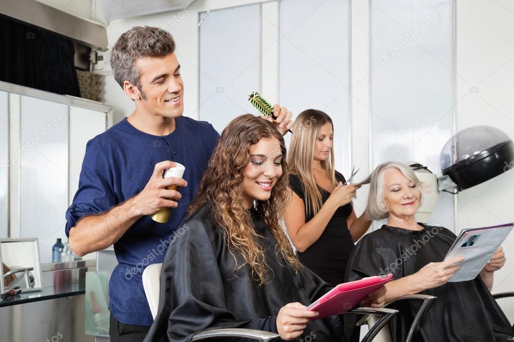 Cliente do sexo feminino feliz usando secador de cabelo no salão