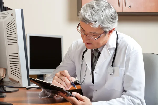 Médecin lisant assis au bureau — Photo