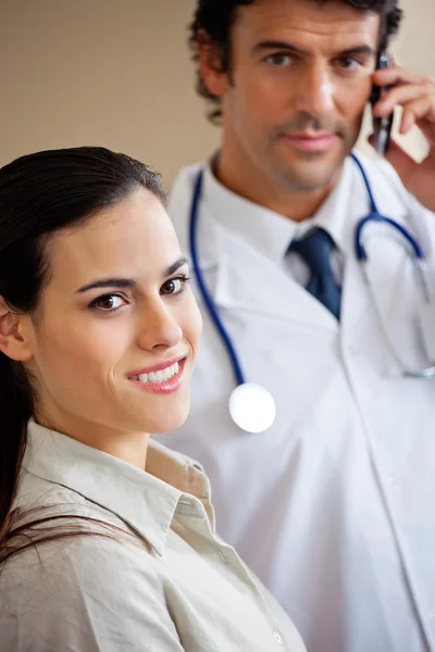 Женщина улыбается, когда доктор стоит на заднем плане — стоковое фото