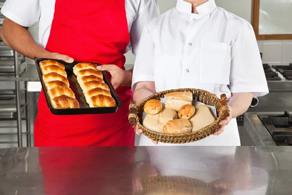 Chefs segurando pães cozidos na cozinha — Fotografia de Stock