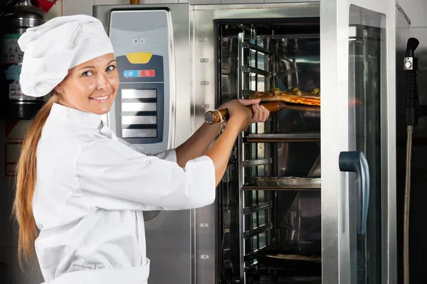 Chef colocando pizza en el horno — Foto de Stock