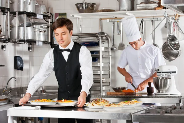 Garçom e Chef trabalhando na cozinha — Fotografia de Stock