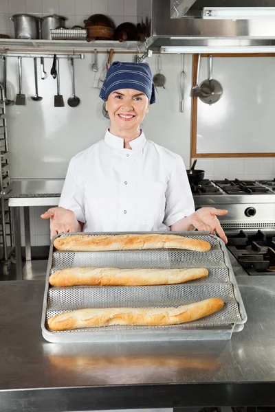 Kvinnliga kock presentera bakade limpor — Stockfoto