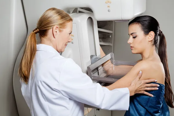 Arzt hilft Patientin bei Mammografie Stockbild