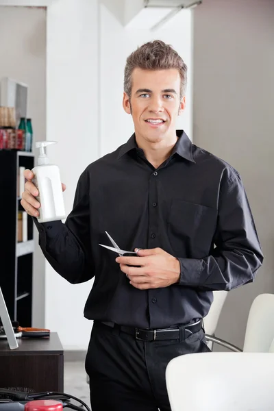 Friseur mit Schere präsentiert Shampoo-Flasche — Stockfoto