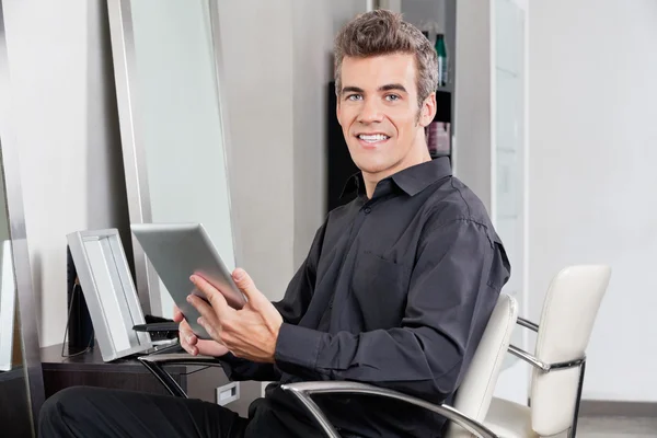Cliente masculino com tablet digital sentado no salão — Fotografia de Stock