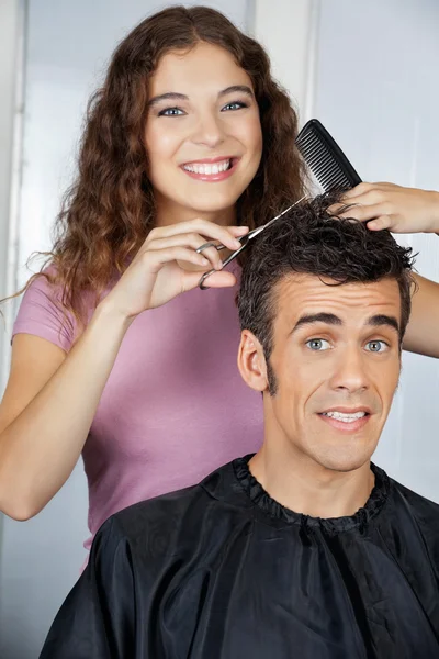 Cabeleireiro feliz cortando o cabelo do cliente no salão — Fotografia de Stock