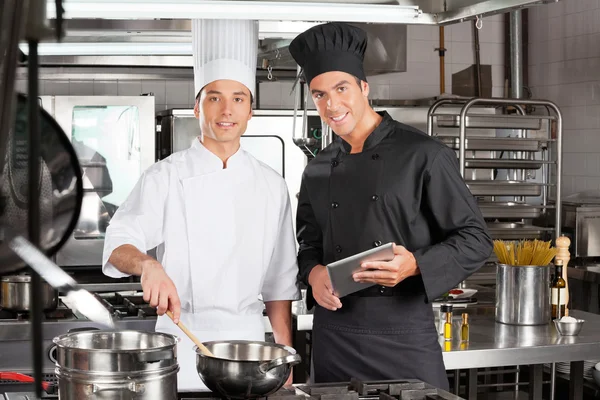 Chefs felizes com comida de cozinha de tablet digital — Fotografia de Stock