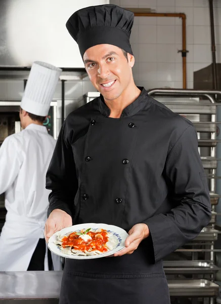 Chef-kok voorstellende schotel in keuken — Stockfoto