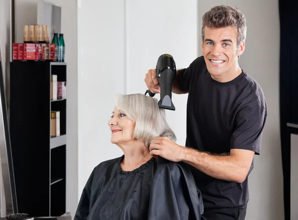 Мужской парикмахер с сушилкой Установка волос клиента — стоковое фото