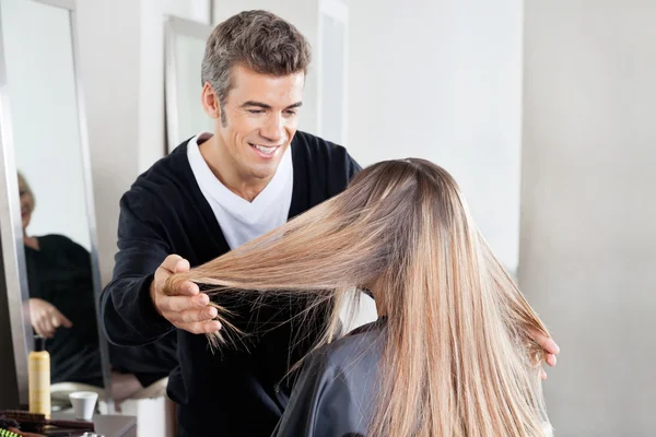 Coiffeur examinant les cheveux du client au salon — Photo