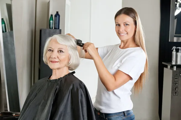 Frisör strykning kvinnans hår — Stockfoto