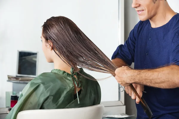 Männlicher Friseur kämmt das nasse Haar seiner Kundin — Stockfoto