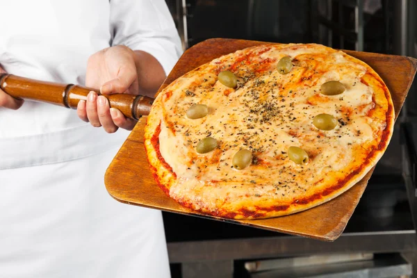 Koch hält Pizza auf Schaufel — Stockfoto