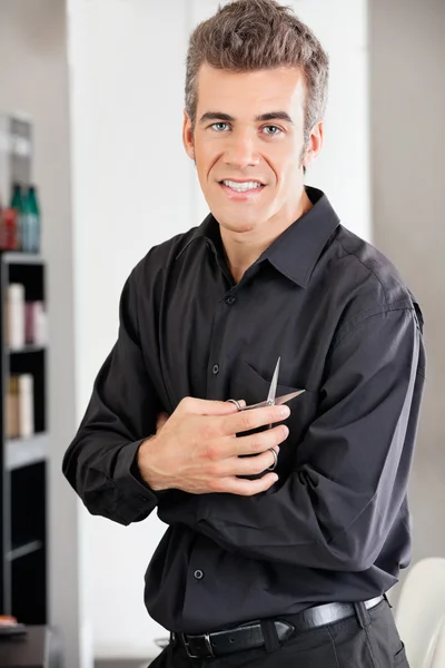 Peluquero sosteniendo tijeras en el salón — Foto de Stock