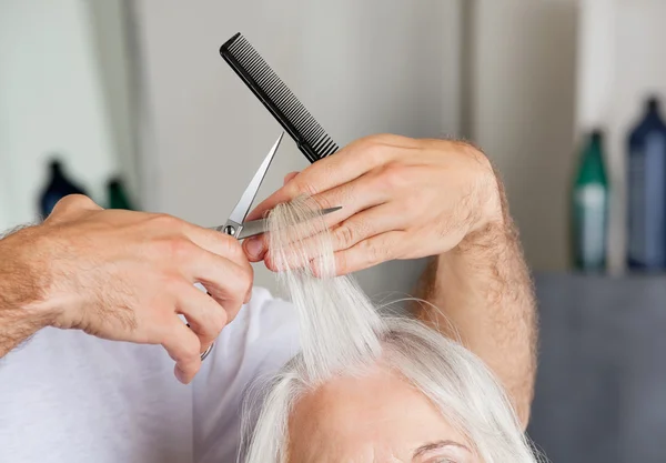 Рука парикмахера стрижет волосы в гостиной — стоковое фото