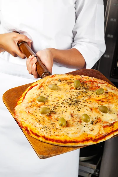Köchin hält Pizza auf Schaufel — Stockfoto