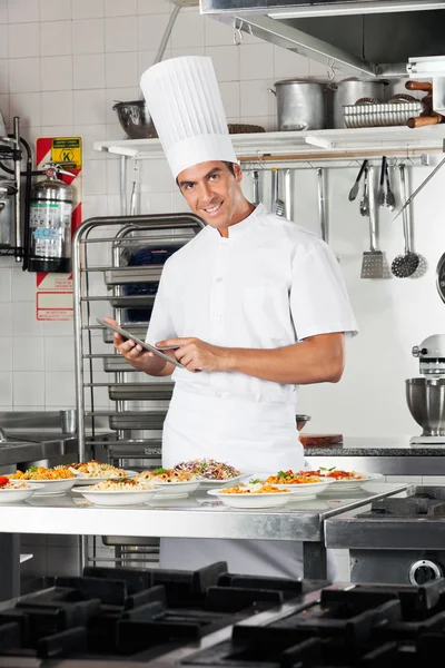 Gelukkig chef-kok met digitale tablet lijst van pasta's controleren — Stockfoto