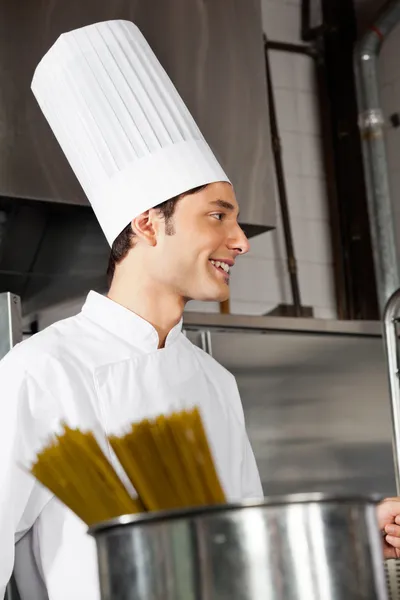 Молодой шеф-повар стоит на кухне — стоковое фото