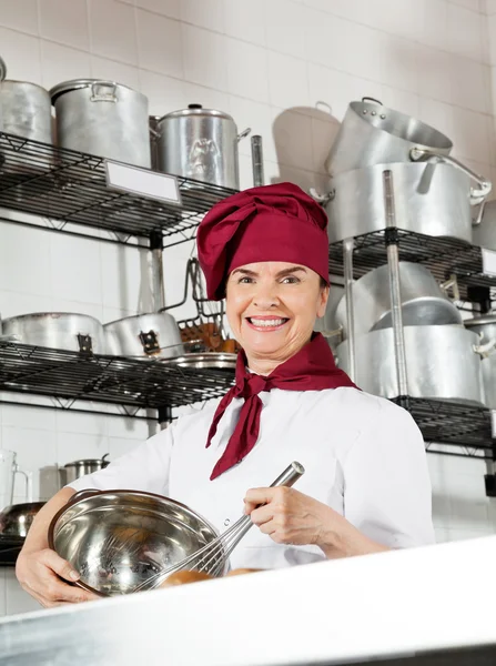 Vrouwelijke chef-kok mengen ei met draad vliegenmepper in kom — Stockfoto