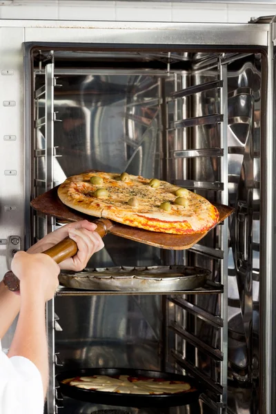 Kockens händer utsläppande Pizza i ugnen — Stockfoto