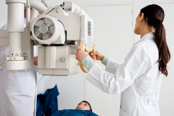 Radióloga femenina que realiza radiografía en paciente —  Fotos de Stock