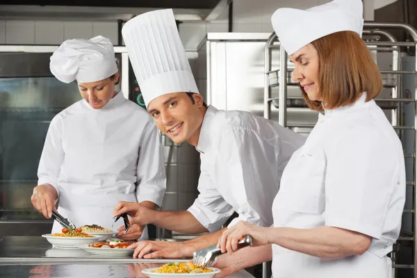 Chef masculino com colegas que trabalham na cozinha — Fotografia de Stock