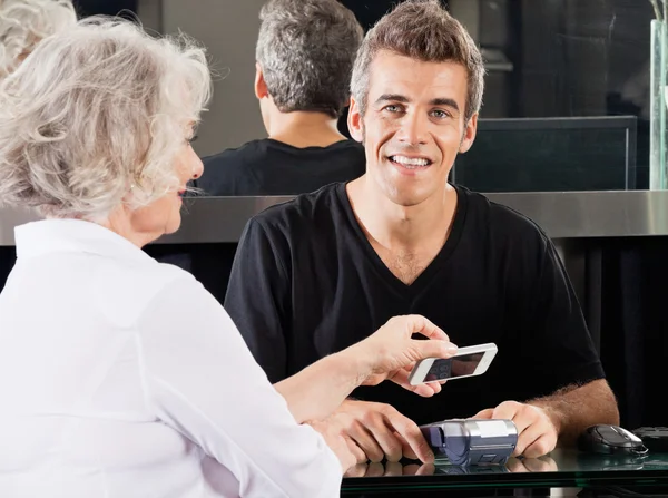 Coiffeur avec femme payant par téléphone portable — Photo