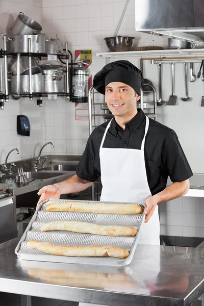 Männerkoch präsentiert Laibe in Küche — Stockfoto