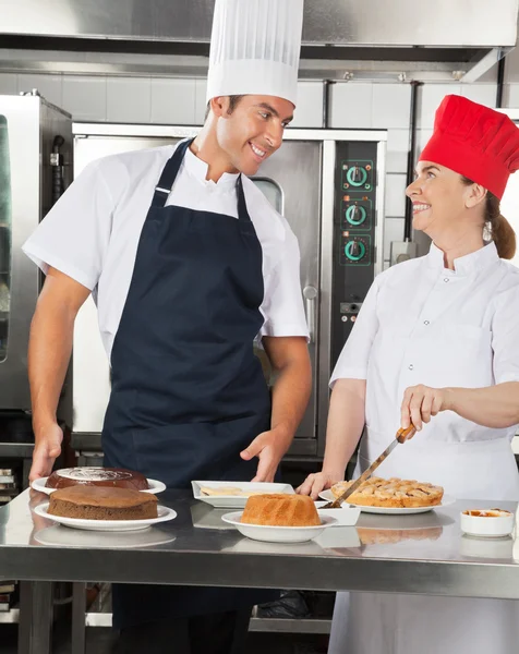 Chefs felizes preparando pratos doces na cozinha — Fotografia de Stock