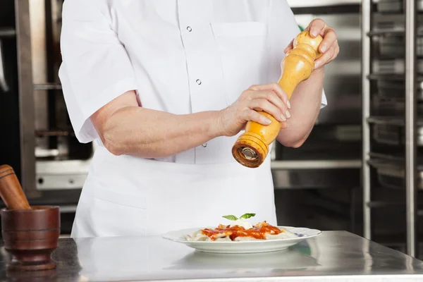 Chef femminile con piatto di condimento al macinapepe — Foto Stock