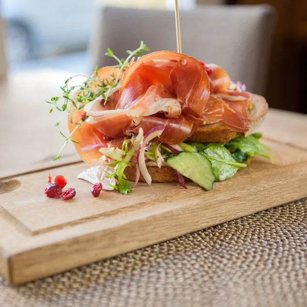 Parma ham sandwich op houten plaat — Stockfoto