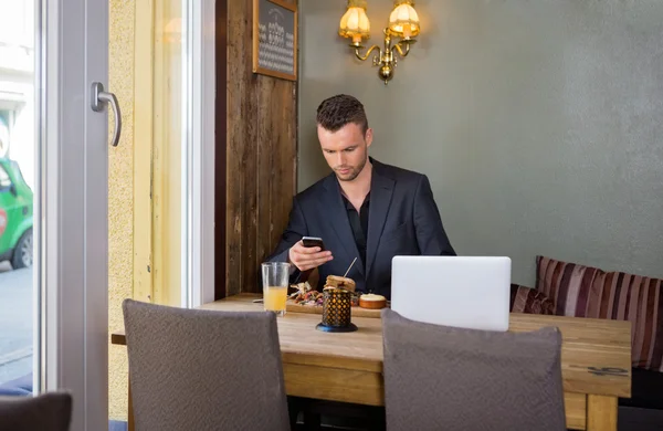 Деловой человек отправляет сообщения по мобильному телефону во время еды — стоковое фото
