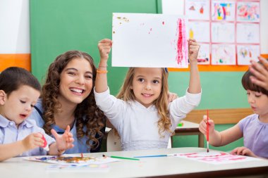 öğretmeni masada çizim gösteren kız