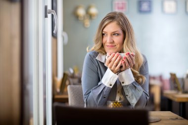 uzağa bakarken kahve fincanı tutan kadın