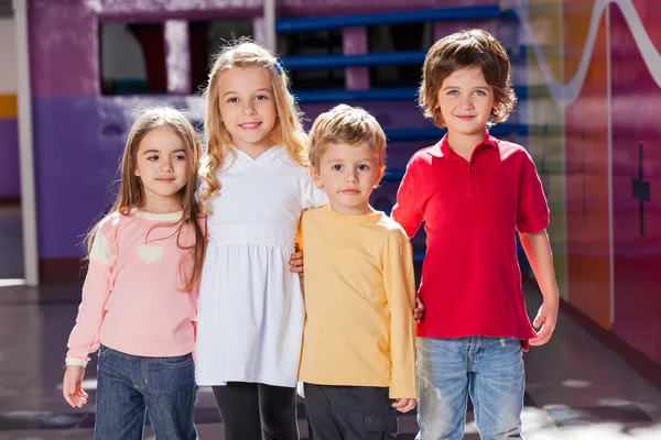 Bambini in piedi braccia intorno alla scuola materna — Foto Stock