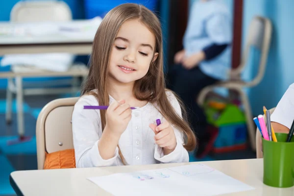 Mädchen schaut Skizzenstift im Klassenzimmer an — Stockfoto