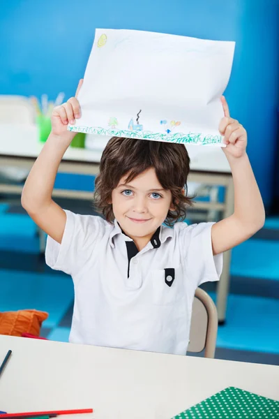 Menino mostrando papel de desenho na sala de aula — Fotografia de Stock