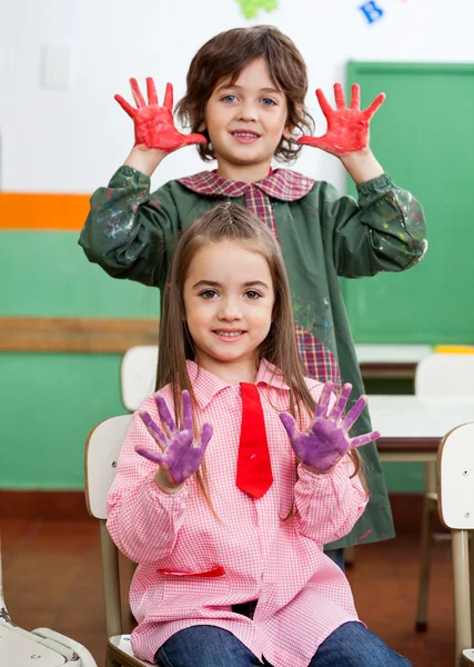 Niño y niña mostrando las manos coloreadas en el aula —  Fotos de Stock