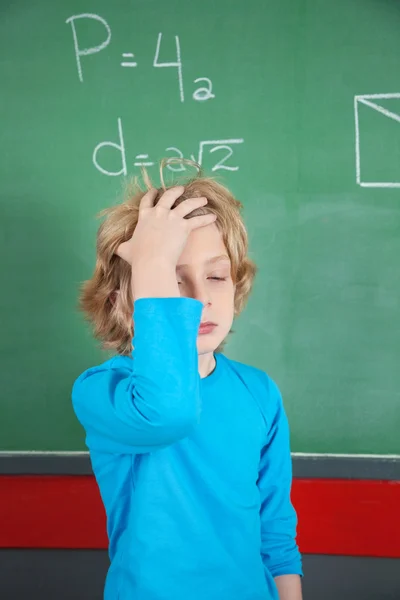 Sad Schoolboy Standing By Board In Classroom — Stock Photo, Image